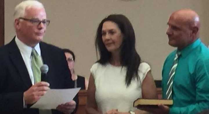 Ridgewood Attorney Matthew Rogers, left, swears in Ridgewood Mayor Susan Knudsen as her husband, John, looks on.