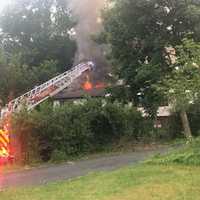 <p>Flames shoot through the roof of the home.</p>