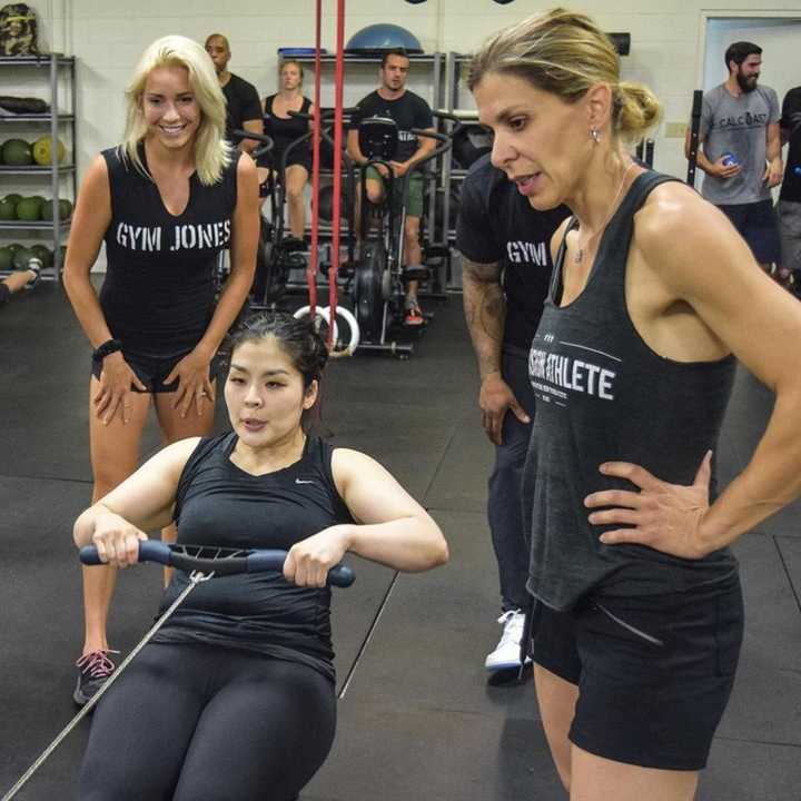 Anyssa Lucena, right, encourages Gym Jones athletes to dig deep on the rowing machine.