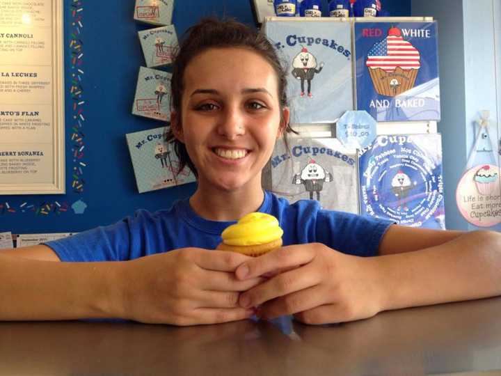 Clifton staff member, Marissa Rossi, with her favorite cupcake, the Lemon Drop: yellow cake filled with lemon pie filling and topped with cream cheese icing.