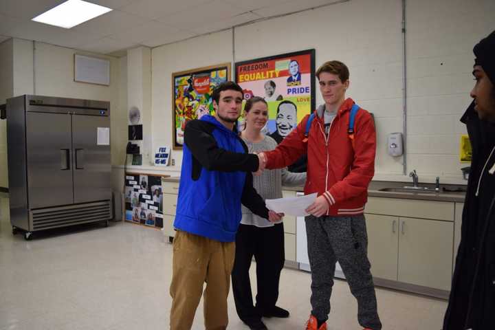 Fox Meadow senior Daniel Box (left) presents an award to fellow senior John Rodak (right) as Principal Nicole Murphy looks on. Fox Meadow recognized 36 students Friday for academic achievement and attendance.