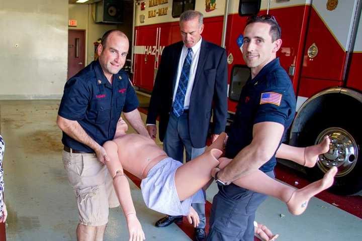 Chief Tom Loreto, left, and a Mahwah fireman lift the new, 165-pound life-like dummy the department purchased with the new grant.