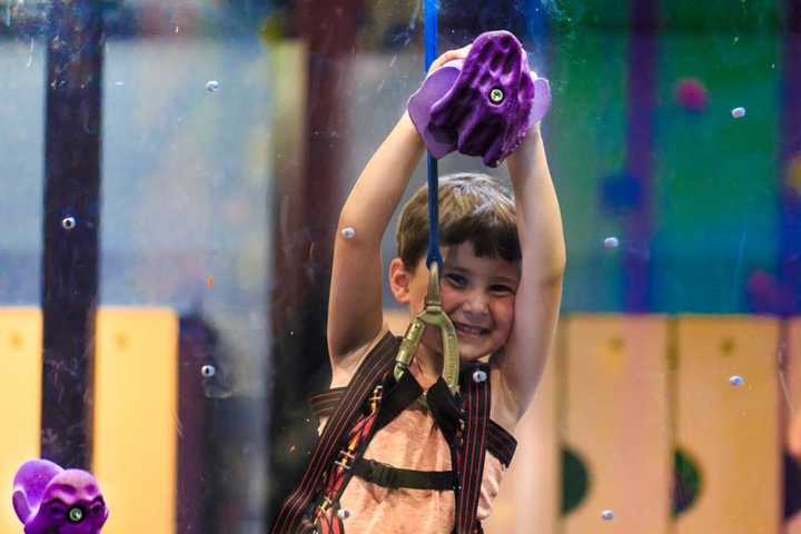 A young climber scales the plexiglass wall at Northvale&#x27;s High Exposure, LLC.