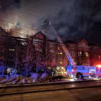 <p>Fire crews attack the blaze from above in the condo building on Richards Avenue in Norwalk on Monday evening.</p>