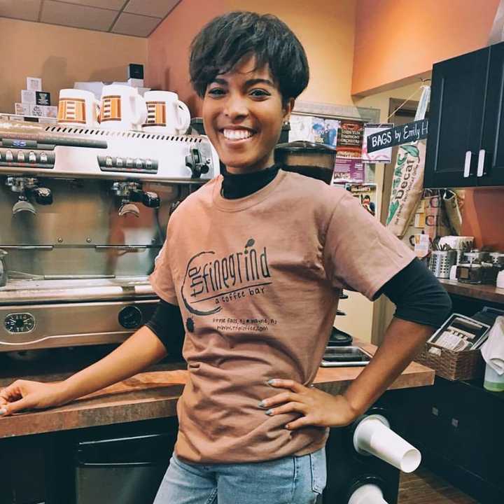 The Fine Grind barista Amani models the shop&#x27;s new T-shirts, now available in Wayne.