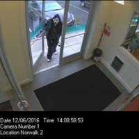 <p>The suspect enters the First County Bank in Norwalk wearing a ghost mask, a black leather jacket, and a black-hooded sweatshirt.</p>