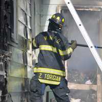 <p>A Central Nyack firefighters works to knock down a fire at a Waldron Avenue home that was filled with garbage.</p>