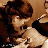 <p>Laura Hoyos of Englewood, who owns Paint 2 Smile, works on a belly-painting client.</p>