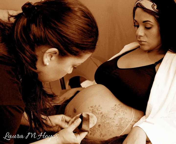 Laura Hoyos of Englewood, who owns Paint 2 Smile, works on a belly-painting client.