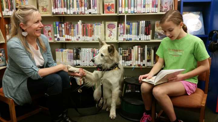 Catherine, a trainer, sits with Ben the dog and Kristina, a patron at Franklin Lakes Public library during the December PAWS event. 