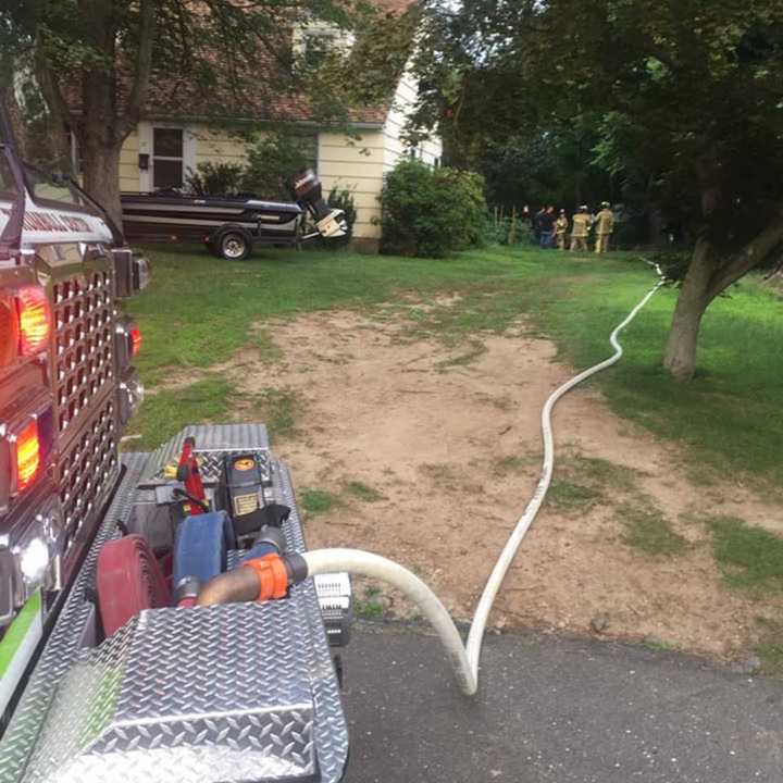 Crews from the Trumbull Volunteer Fire Company douse a burning pile of brush and debris behind a home on Ruth Street on Sunday evening.