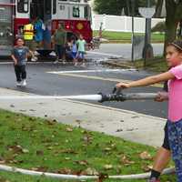 <p>A New Milford girl operates a fire hose with assistance from a firefighter.</p>