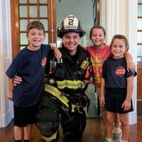 <p>Hackensack Leitenant Mike Oates with his children, who attend the Fairmount School. Firefighters on Monday visited Fairmount, where they made a presentation and let the students try on their bunker gear.</p>