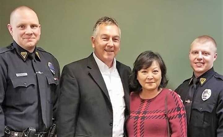 Officer Matthew Rork (left) and Officer Brian Stevens flank the woman and her fiancé.