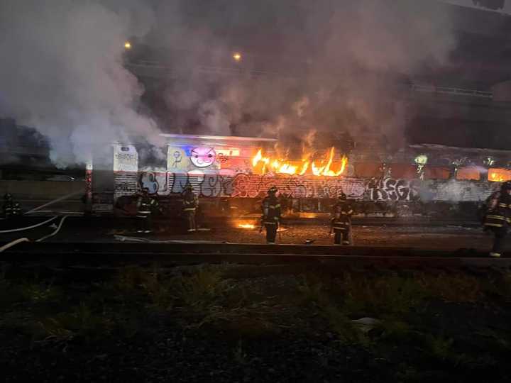 Flames spewing from the abandoned train car near the MBTA commuter rail maintenance facility in Somerville