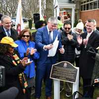 <p>Malverne Mayor Keith Corbett unveils a plaque commemorating the newly renamed Acorn Way during a ceremony held outside Maurice Downing Elementary School on Thursday, Jan. 26.</p>