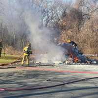 <p>Firefighters work to put out a trash fire in South Windsor in the area of Farmstead Drive and Brook Street.</p>