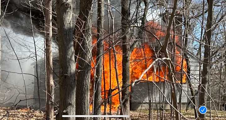 Flames shoot from a home at 55 Belknap Street in Westborough where an elderly woman was found dead