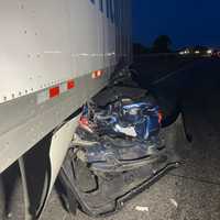 <p>The rear bumper of the crushed sedan sticking out from under the Walmart tractor-trailer.</p>