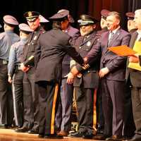 <p>Bergen County Police Academy Class #131 graduate congratulated by county Prosecutor Mark Musella, flanked by Sheriff Anthony Cureton (left) and County Executive Jim Tedesco.</p>