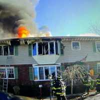 <p>Flames shot through the roof of the Walnut Street home in Ridgefield.</p>