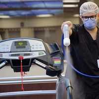 <p>A Holy Name Health nurse sprays down a treadmill</p>