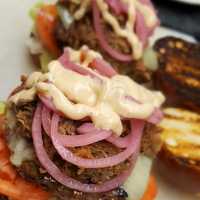 <p>Hair of the Dog&#x27;s &quot;All Hellz Breakin&#x27; Loose&quot; burger, an eight ounce patty topped with maple bourbon braised pork, bacon, pickled red onion, sharp cheddar, smoky remoulade, lettuce and tomato on a pretzel roll</p>