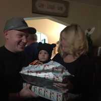 <p>Baby Jackson opens gifts from Santa, as Detective David Boone, and his elves.</p>