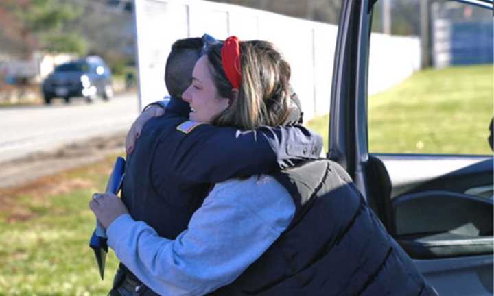 Officer Karen Capuano gets a hug from a driver after giving the driver a gift card, along with a warning about a low-level traffic violation, in an effort to spread holiday cheer while also enforcing traffic laws.