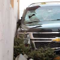 <p>The Chevrolet Suburban livery vehicle ended up wedged between the building and the bin.</p>