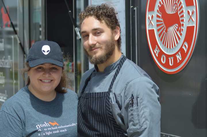 Maycie Maringer and Sam Ralbovsky pose in front of the Nosh Hound food truck in Stamford Tuesday. Ralbovsky is a Stamford native.