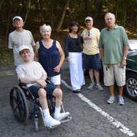 <p>A group of people pose beside one of the cars.</p>