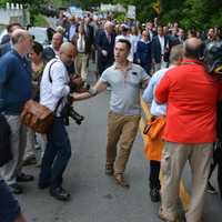 <p>A member of Hillary Clinton&#x27;s entourage (center, in grey shirt) motions a press scrum to move back as New Castle&#x27;s Memorial Day parade gets underway.</p>