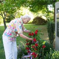 <p>Lynn Watson, of the Green Acres Garden Club, places a wreath at the 9/11 memorial.</p>