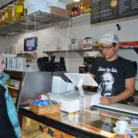 <p>Owner Breno Donatti rings up a customer at his latest Winfield Street Deli location near the bridge in downtown Westport.</p>