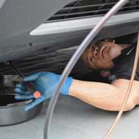 <p>Roberto Gonzalez working under a car on a service road off Route 17 in Rutherford.</p>