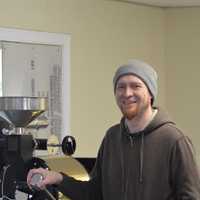 <p>Sherman resident John Rich, owner of Sacred Grounds Coffee Roasters, poses in front of his coffee roaster Monday</p>