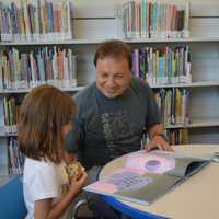 <p>Peter Tuccino reads a book with his daughter, Emma, 6</p>