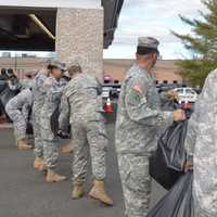 <p>Military members form an assembly line to load vehicles with gifts.</p>