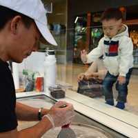 <p>A young customer watching Eason Wang of Elmwood Park at work.</p>