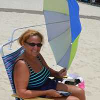 <p>Lori Campeau of Westwood makes her own shade so she can read her Kindle at Crestwood Lake in Allendale.</p>