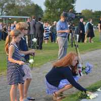 <p>Friends and family leave white roses on the names at the 9/11 memorial in Westport Thursday.</p>