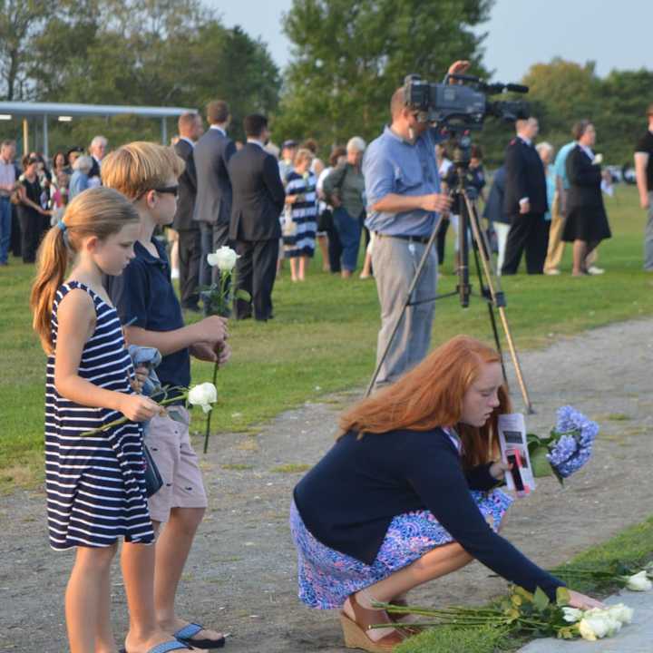 Friends and family leave white roses on the names at the 9/11 memorial in Westport Thursday.
