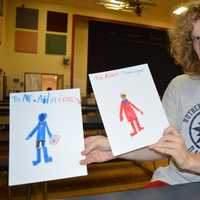 <p>Aidan shows off his students&#x27; artwork</p>