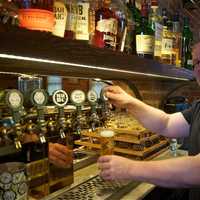 <p>A bartender draws a craft beer at Mill House Brewery.</p>