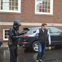 <p>A shopper hands his keys off to a rain-soaked valet outside the new Bedford Square development in downtown Westport.</p>