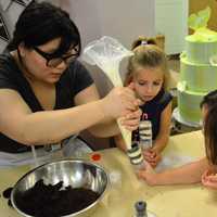 <p>An instructor helps students in the Buttercup Bakery Camp.</p>