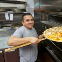 <p>A pizza chef pulls a pie out of the oven at Amalfi Pizzeria and Restaurant.</p>