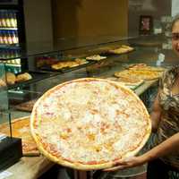 <p>Shelby Squillante of Amalfi Pizzeria holds one of the restaurant&#x27;s massive, 24-inch pies.</p>