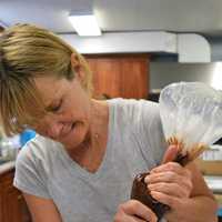 <p>Tamyl Dunwoody helps some girls top off one of their cakes.</p>